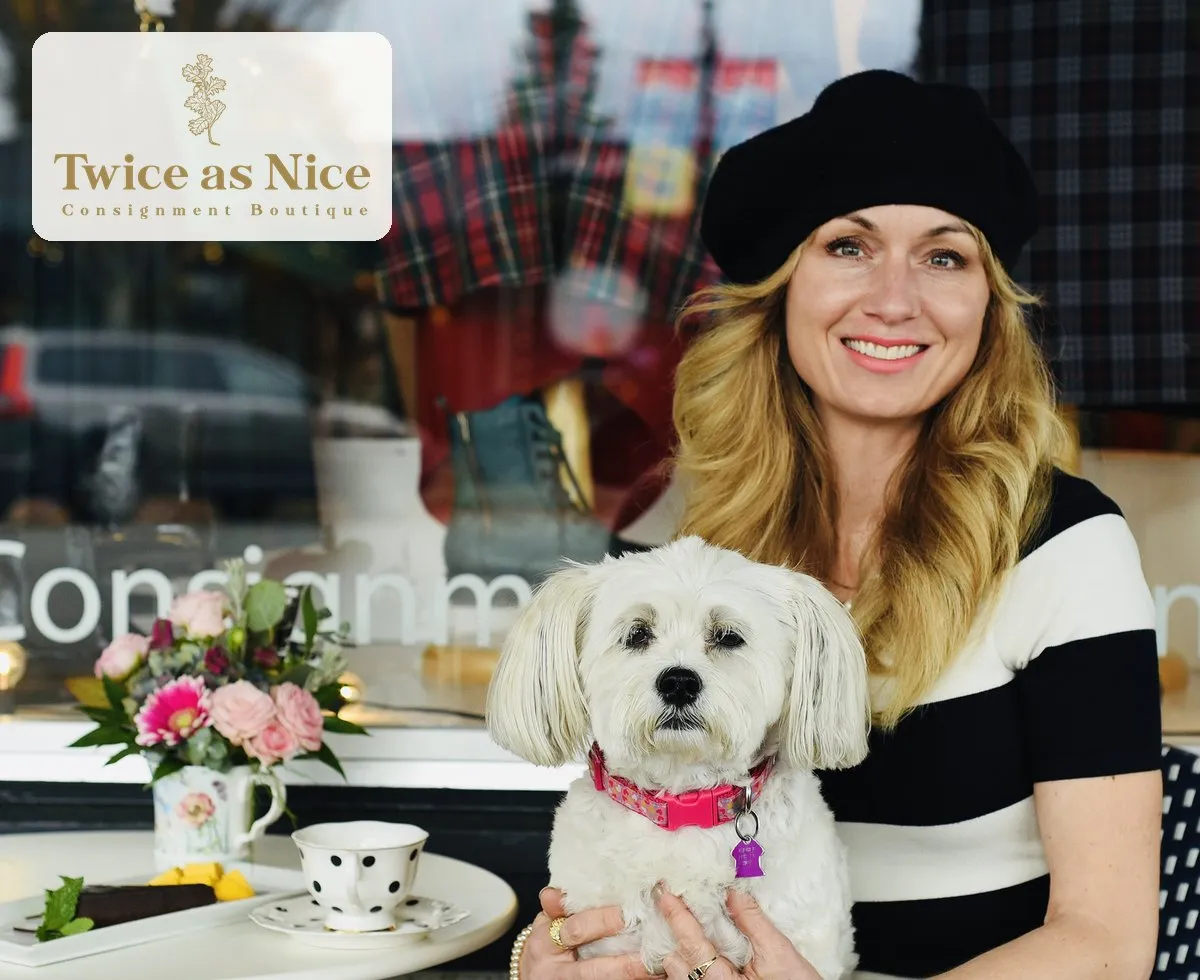 A smiling woman in a black beret holds a small white dog outside the Twice as Nice consignment shop window, with the Twice as Nice logo in the corner