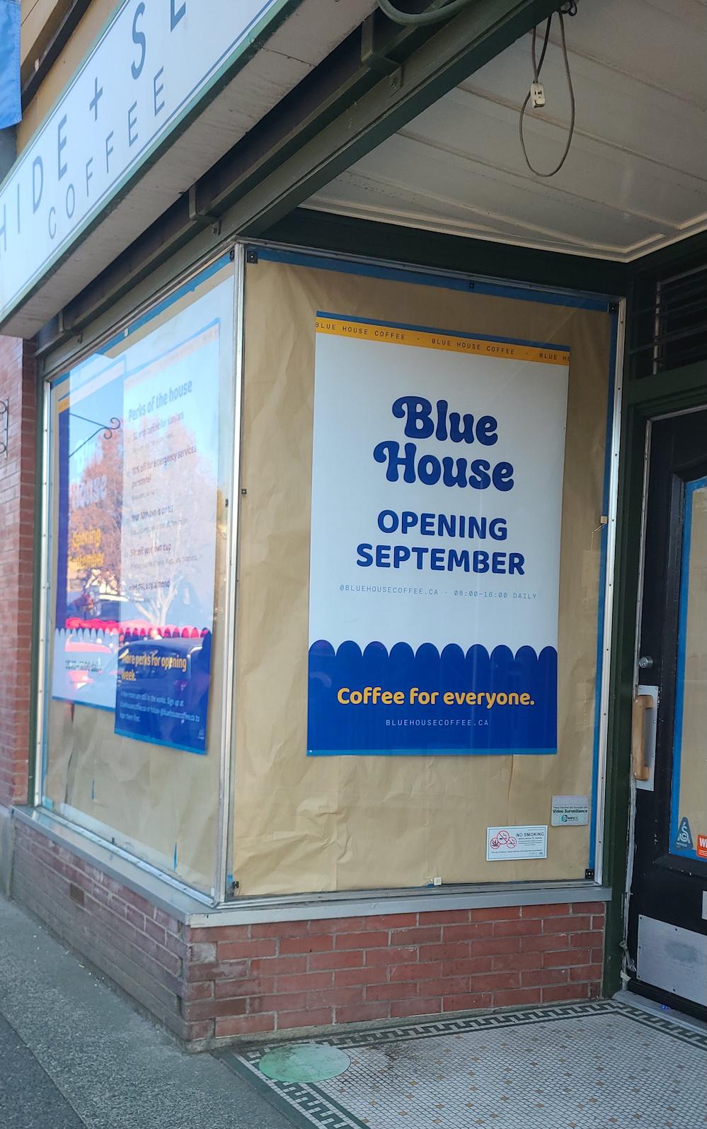 A paper sign in the former Hide + Seek window announcing Blue House Coffee is opening in September